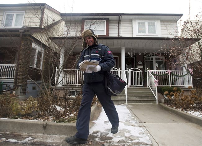 A Canada Post employee delivers mail and parcels to residential homes in Toronto on Wednesday, Dec. 11, 2013. The federal Crown corporation plans to phase out home delivery within the next five years, replacing foot delivery with community mail boxes. Canada Post says says about 6,000 to 8,000 positions will be eliminated over the same time period, mainly through attrition. THE CANADIAN PRESS/Nathan Denette