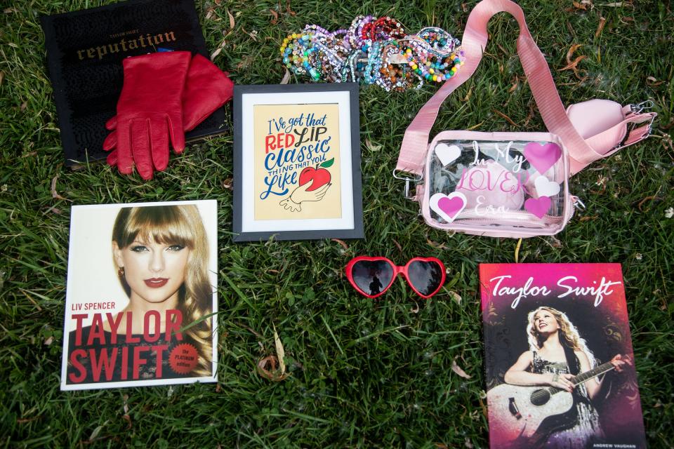 Emily Schenk, 30, of Milford, shows off some of her Taylor Swift collectibles include a VIP book from her 2016 Reputation tour stop in Detroit and red heart shaped sunglasses from the album "22" at Central Park in Milford on Tuesday, June 6, 2023.