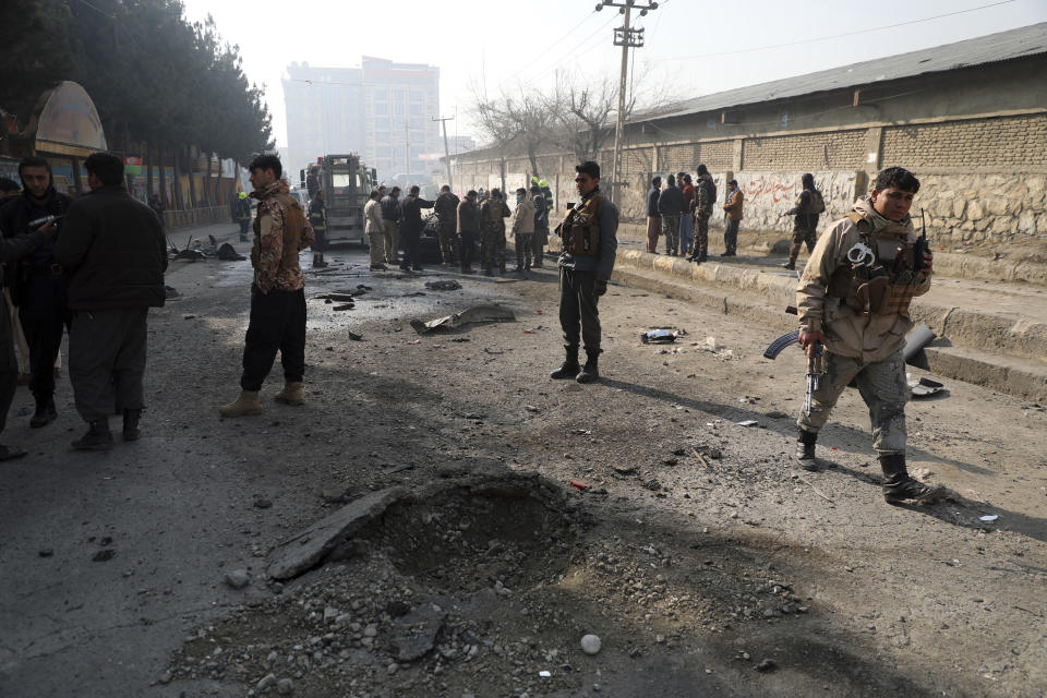 Afghan security officers inspect the site of a bombing attack in Kabul, Afghanistan, Sunday, Jan. 10, 2021. A roadside bomb exploded in Afghanistan's capital Sunday, killing at least a few people in a vehicle, the latest attack to take place even as government negotiators are in Qatar to resume peace talks with the Taliban. (AP Photo/Rahmat Gul)