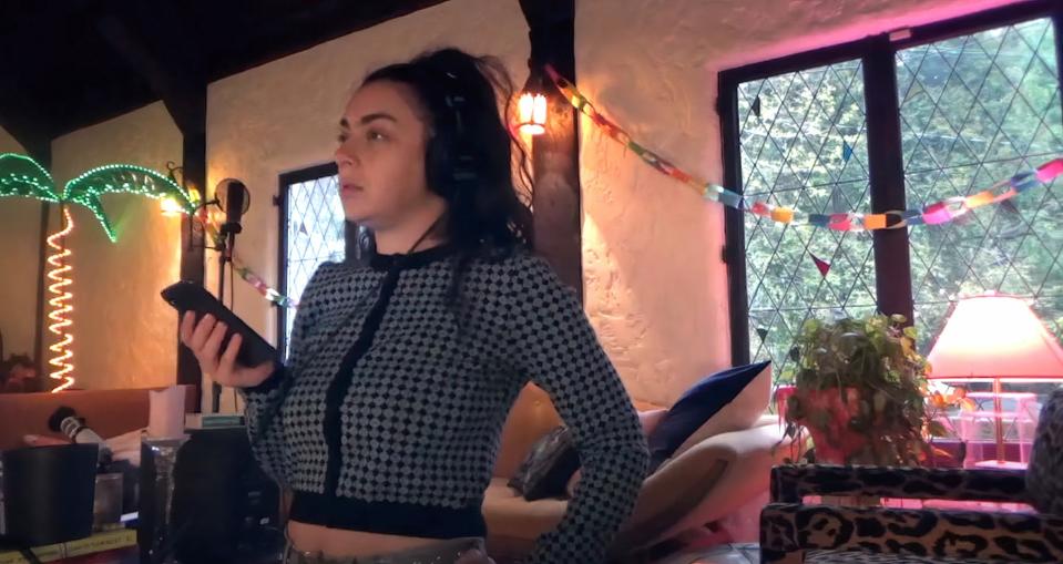 Charli XCX listens to her phone on headphones