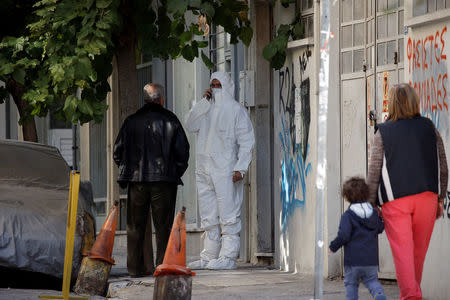 A forensics officer stands at the entrance of a building following an operation in which Greek security services raided Athens apartments and found bomb-making equipment, detaining nine people on suspected links to a leftist militant group outlawed in Turkey, in Athens, Greece, November 28, 2017. REUTERS/Alkis Konstantinidis