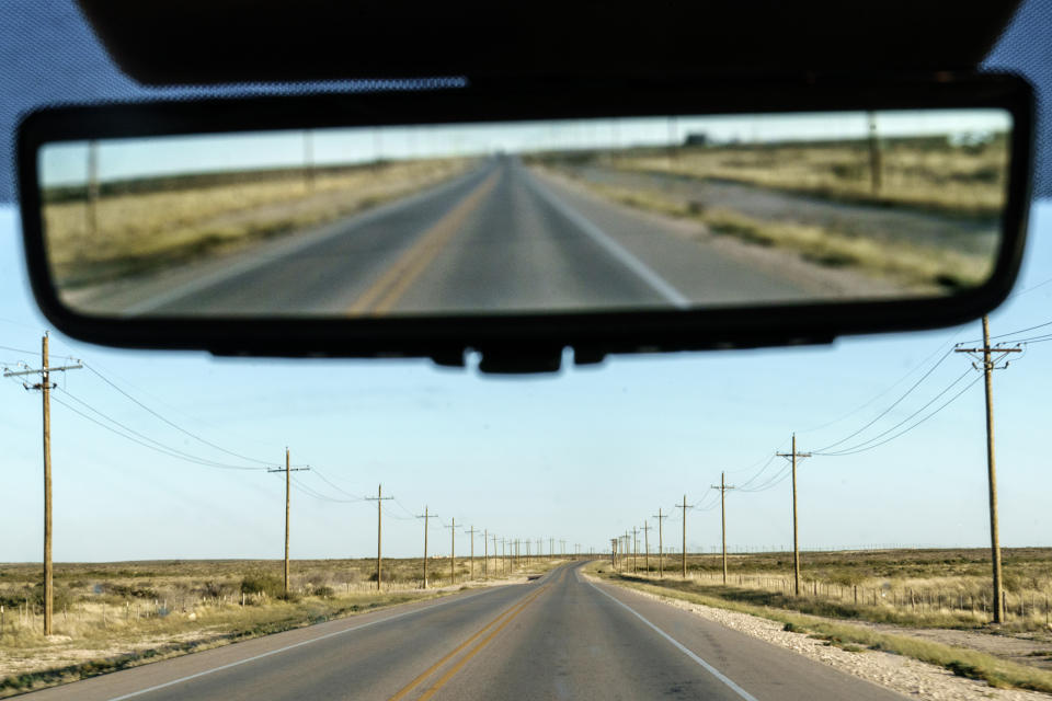 Utility poles line a road through the Permian Basin in Mentone, Texas, Thursday, Oct. 14, 2021. The Permian, a 250-mile-wide bone-dry expanse along the Texas-New Mexico border, was the bottom of a shallow sea a billion years ago. (AP Photo/David Goldman)