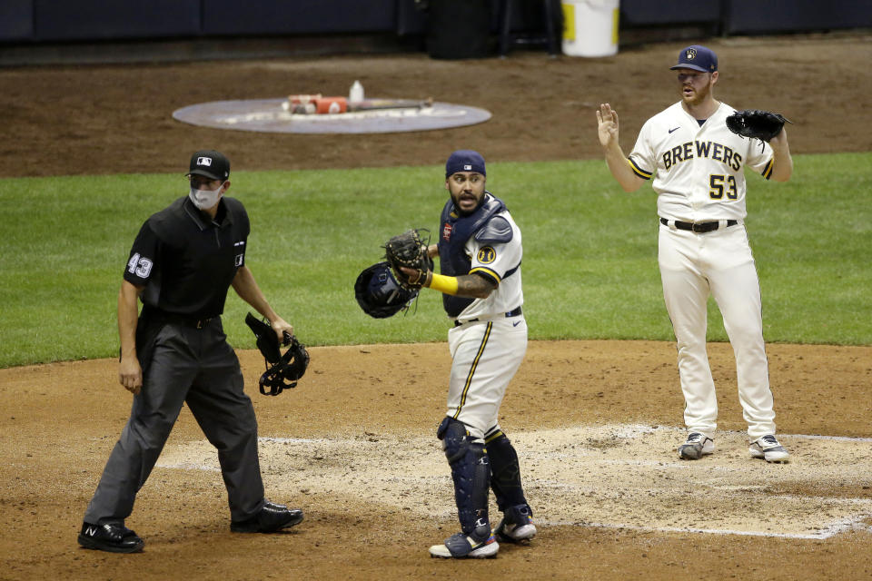 Milwaukee Brewers' Brandon Woodruff (53) and Omar Narvaez react after an umpire called a runner safe during the fifth inning of a baseball game against the Cincinnati Reds Tuesday, Aug. 25, 2020, in Milwaukee. The call was changed to an out. (AP Photo/Aaron Gash)