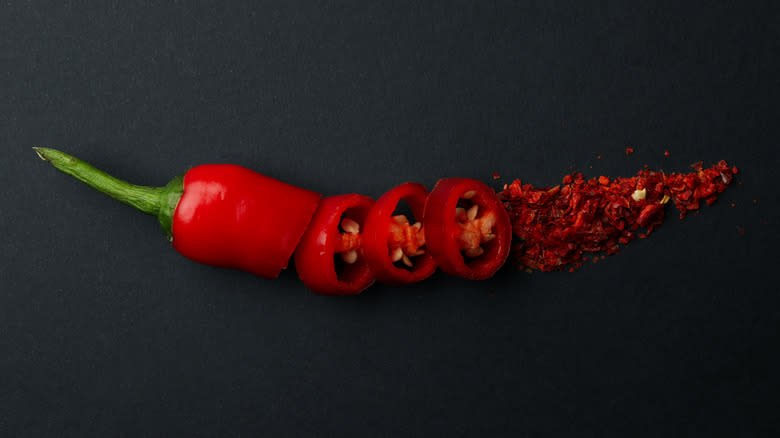 red chili pepper sliced and ground on a black surface