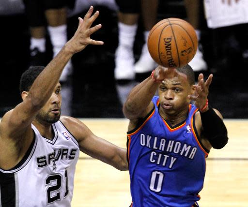 Russell Westbrook, #0 de Oklahoma City Thunder, pasa el balón marcado por Tim Duncan, #21 de San Antonio Spurs, en partido inicial de la serie final de la Conferencia Oeste de la NBA en el AT&T Center el 19 de mayo de 2014 en San Antonio, Texas. (GETTY IMAGES NORTH AMERICA/AFP | Chris Covatta)