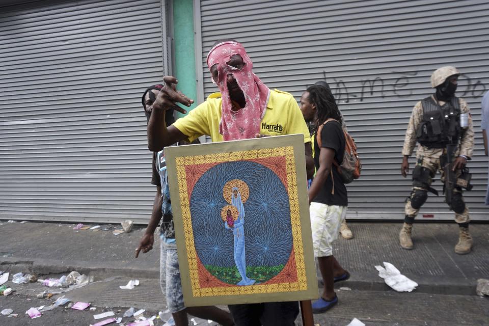 Un hombre posa con una pintura después de saquear una tienda durante una protesta para exigir la renuncia del presidente Jovenel Moïse en Puerto Príncipe, el viernes 27 de septiembre de 2019. (AP Foto/Edris Fortune)