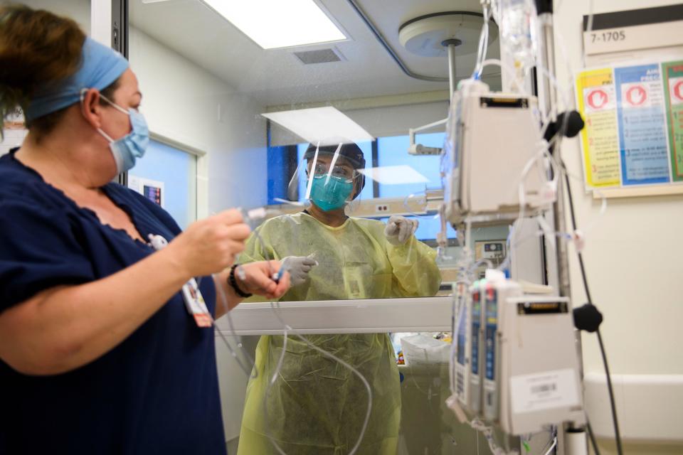 A nurse wearing personal protective equipment (PPE) communicates through a glass door while attending to a patient in a COVID-19 intensive care unit (ICU) at Martin Luther King Jr. (MLK) Community Hospital in Southern California. / Credit: PATRICK T. FALLON/AFP via Getty Images