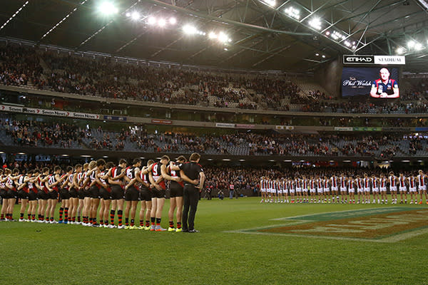 Saints and Bombers players pause for a moment's silence.