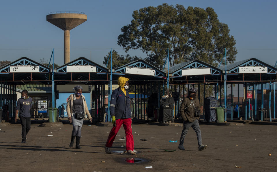 Stranded commuters walks away from a deserted taxi rank in Katlehong, South Africa, Monday, June 22, 2020, as taxi drivers affiliated to the SA National Taxi Council (Santaco) protested against what it believes to be insufficient government relief offered to the industry. South Africa's largest city, Johannesburg, has been hit by a strike by mini-bus taxis, preventing many thousands of people from getting to work on Monday, as the country reopens its economy even as cases of COVID-19 are increasing. (AP Photo/Themba Hadebe)