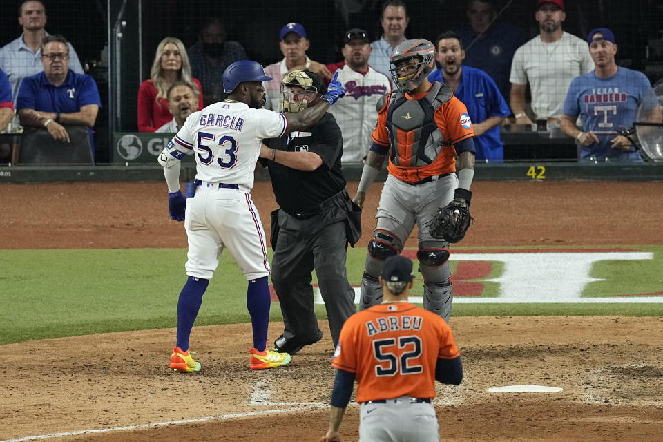 Texas Rangers' Adolis Garcia (53) is restrained by home plate umpire Marvin Hudson as he yells at Houston Astros catcher Martin Maldonado after being hit by a pitch thrown by relief pitcher Bryan Abreu (52) during the eighth inning in Game 5 of the baseball American League Championship Series Friday, Oct. 20, 2023, in Arlington, Texas. (AP Photo/Tony Gutierrez)
