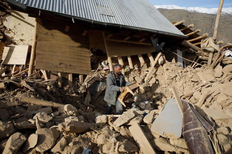 A man clears debris outside a damage house, after an earthquake in Cevrimtas
