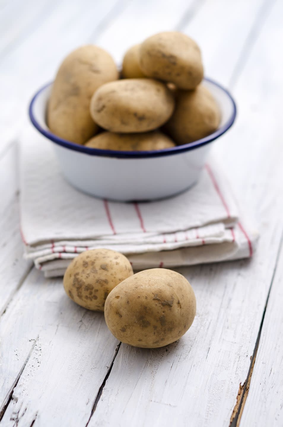 bowl of raw potatoes on folded kitchen towel and wood