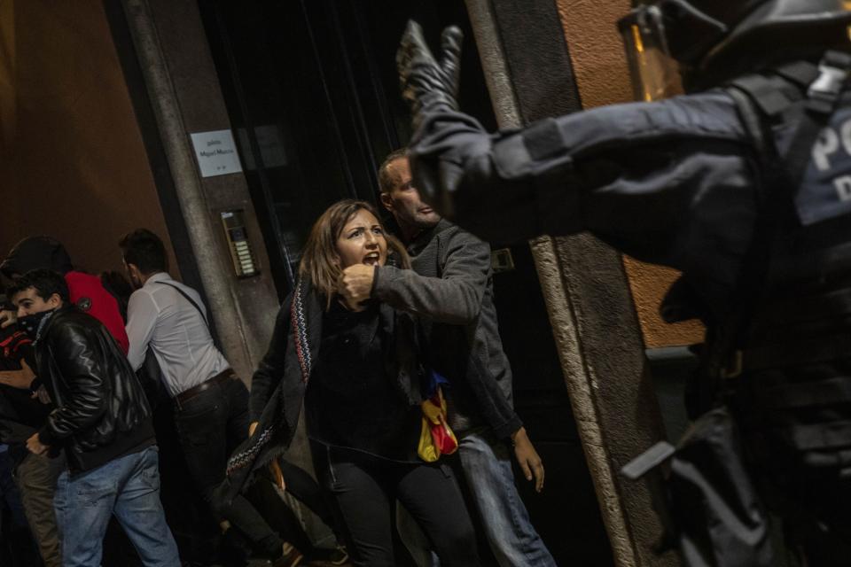 A woman shouts to police officers during clashes in Barcelona, Saturday, Oct. 26, 2019. The clash comes after 350,000 people protested peacefully Saturday against the imprisonment of nine Catalan separatist leaders for their roles in an illegal 2017 secession bid. (AP Photo/Bernat Armangue)