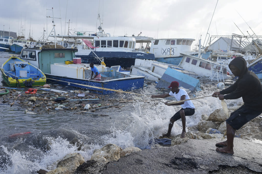 Fishermen pull a boat damaged by Hurricane Beryl