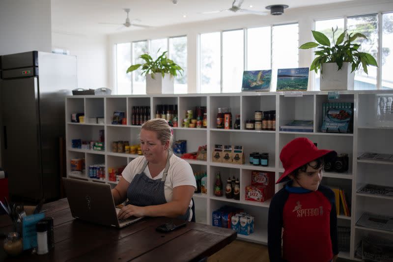 Phoebe Alison, owner of the Hyams Beach Store and Cafe, works on her laptop in Hyams Beach