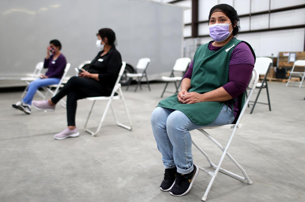 Workers sit in the observation area after receiving a one shot dose of the Johnson & Johnson COVID-19 vaccine at a clinic geared toward agriculture workers organized by TODEC on April 5, 2021, in Riverside, Calif. TODEC Legal Center is an immigrant advocacy organization that is traveling to agriculture sites in Southern California to educate and vaccinate farmworkers while dispelling myths about the vaccines. Essential agriculture workers are among the most likely to contract COVID in California as they often work closely together, lack health insurance and reside in crowded housing conditions.