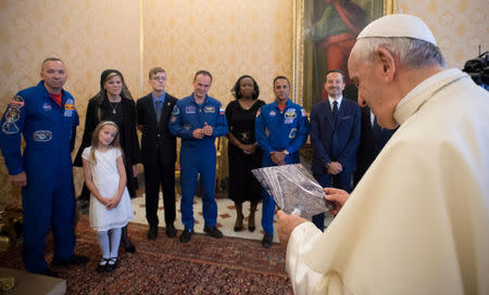 Pope Francis looks at a picture as he meets the crew members of the ISS 53 space mission during a private meeting at the Vatican June 8, 2018. Vatican Media/Handout via REUTERS