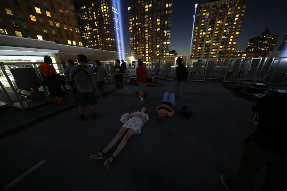 <p>Visitors lie on the ground to view the Tribute in Light on Sept. 5, 2018. (Photo: Gordon Donovan/Yahoo News) </p>