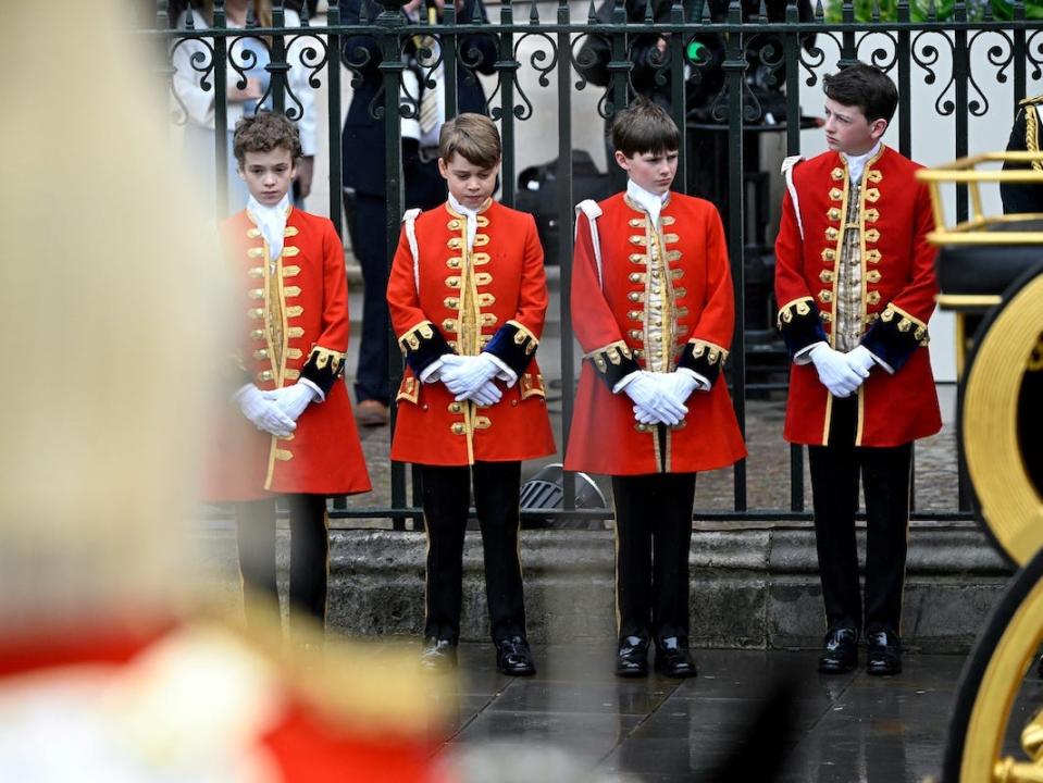 The king's pages of honor stand outside Westminster Abbey (from left to right): Nicholas Barclay, Prince George, Lord Oliver Cholmondeley, and Ralph Tollemache.