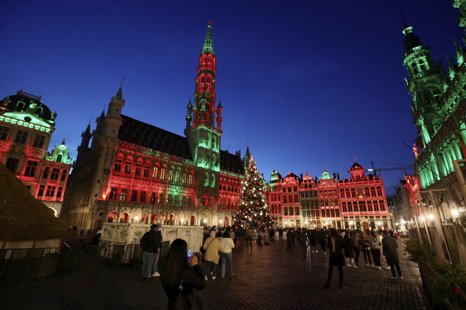 FILE - In this Tuesday, Nov. 24, 2020 file photo, people walk in the historic Grand Place during the official lighting of the Christmas tree in Brussels. Nations are struggling to reconcile cold medical advice with a holiday tradition that calls for big gatherings in often poorly ventilated rooms, where people chat, shout and sing together, providing an ideal conduit for a virus that has killed over 350,000 people in Europe so far. (AP Photo/Olivier Matthys, File)