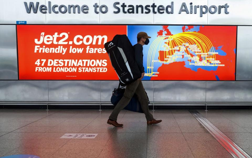 A passenger passes an advertisement for Jet2 at London Stansted