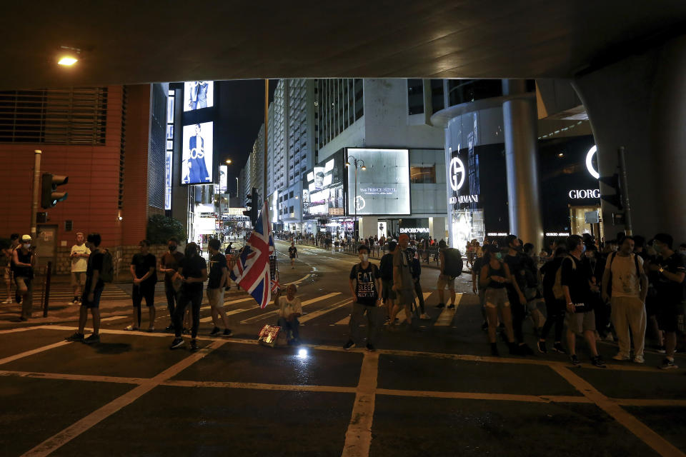 In this July 7, 2019, photo, protesters holding a Union Jack flag block the Canton Road, the one-stop-shop high street of high-end brands also popular with mainland Chinese tourists after a march against government's policy on the extradition bill in Hong Kong. It's still the world's "freest" economy, one of the biggest global financial centers and a scenic haven for tycoons and tourists, but the waves of protests rocking Hong Kong are exposing strains unlikely to dissipate as communist-ruled Beijing's influence grows. (AP Photo/Andy Wong)