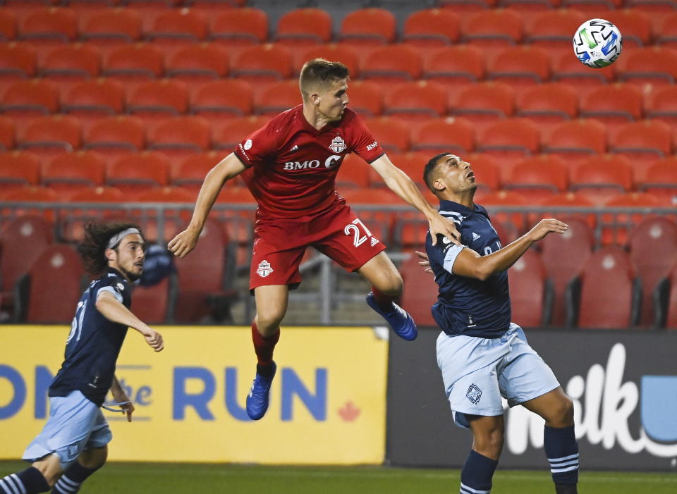 Toronto FC midfielder Liam Fraser (27) battles for the loose ball against Vancouver Whitecaps defender Ali Adnan (53) during the second half of an MLS Canadian Championship soccer game in Toronto on Friday, Aug. 21, 2020. (Nathan Denette/The Canadian Press via AP)