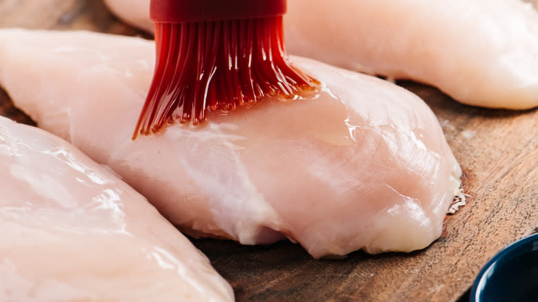 Brushing oil on raw chicken