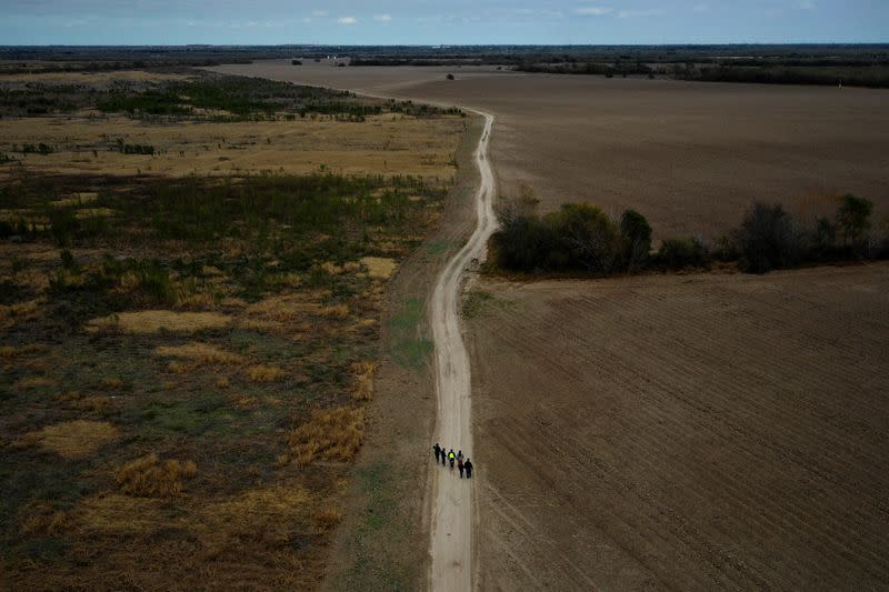 Un grupo de migrantes pasa por tierras de labranza aradas después de cruzar a Estados Unidos desde México, cerca de Penitas