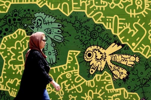 A woman walks in front of a mural in the Iranian capital Tehran on August 6, 2018