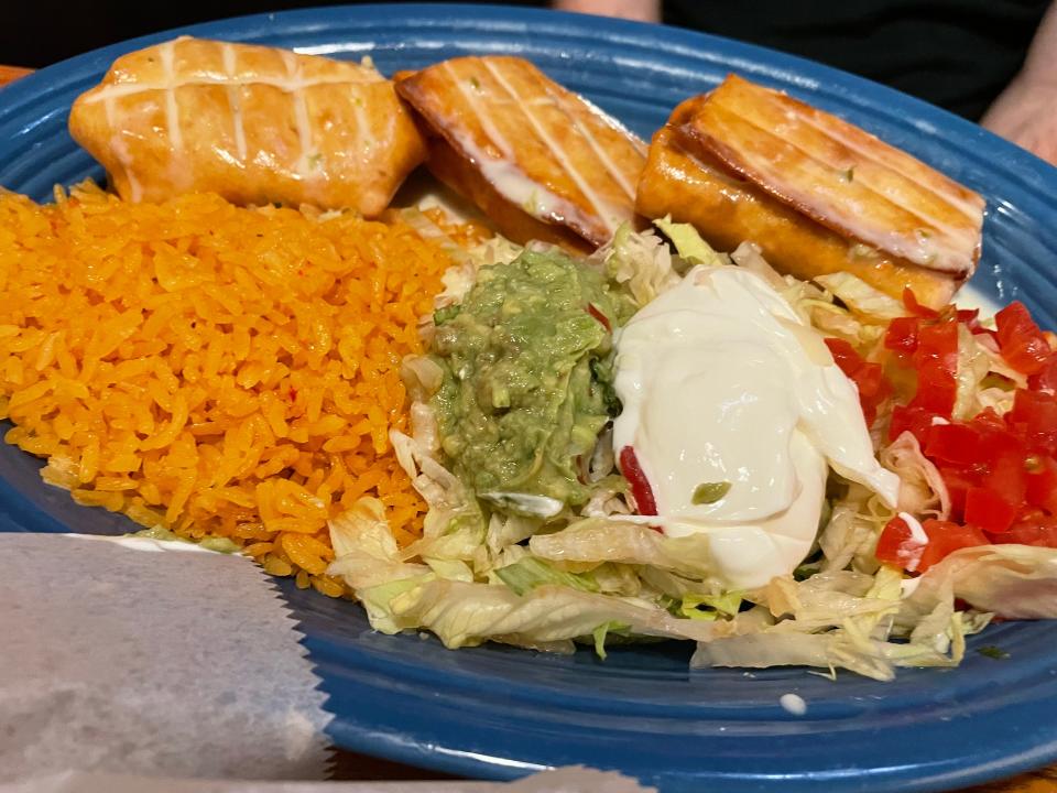 Chimi Trio from Tlaquepaque Mexican Restaurant comes with three chimichangas, one beef, one chicken and one shredded beef served with lettuce, sour cream, sliced tomatoes, guacamole and Spanish rice.