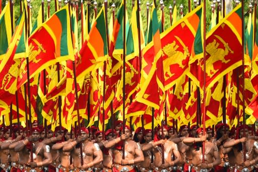 Sri Lankan military personnel in traditional dress holding national flags during Sri Lanka's 72nd Independence Day celebrations in Colombo