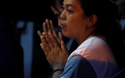 A family member prays near the Tham Luang cave complex, where 12 schoolboys and their football coach are trapped  - Credit: Reuters