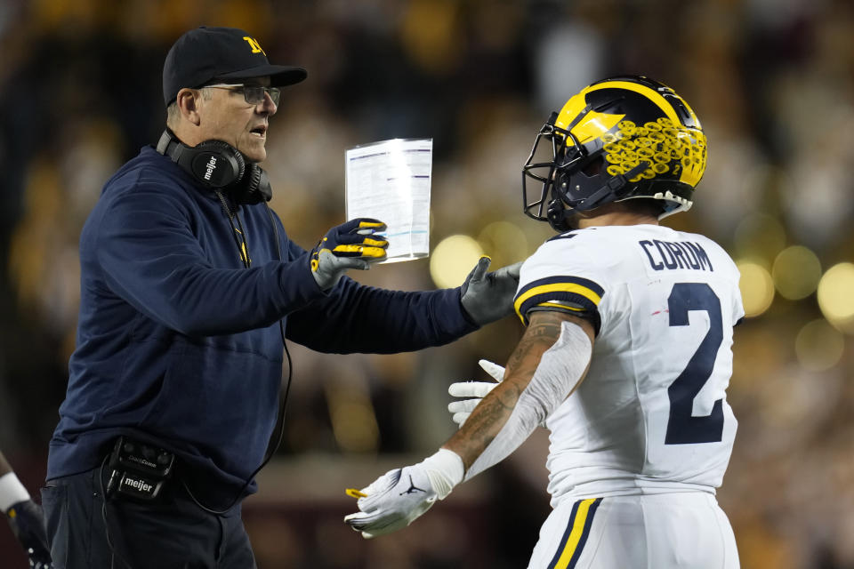 FILE - Michigan head coach Jim Harbaugh celebrates with running back Blake Corum, right, after scoring a touchdown during the first half of an NCAA college football game against Minnesota Saturday, Oct. 7, 2023, in Minneapolis. When Jim Harbaugh and the University of Michigan have their day in court, trying to at least pause punishment from the Big Ten for a sign-stealing scheme, sports law experts will be among those watching how the extraordinary confrontation plays out. (AP Photo/Abbie Parr, File)