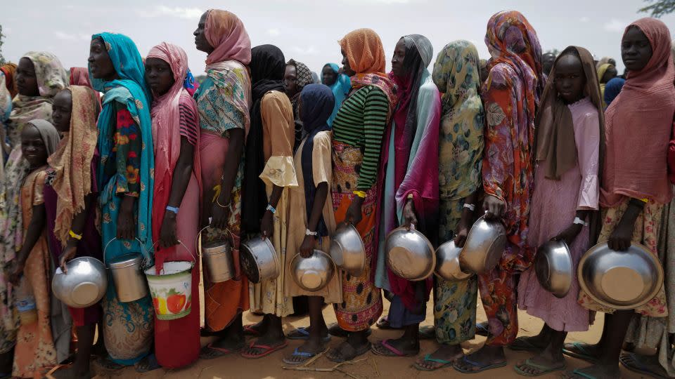 Sudanese women who fled the conflict in El Geneina, in Sudan's Darfur region, line up to receive rice portions from Red Cross volunteers in Ourang on the outskirts of Adre, Chad, on July 25, 2023. - Zohra Bensemra/Reuters