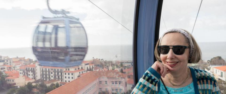 Smiling female tourist in cable car over the city of Funchal in Madiera