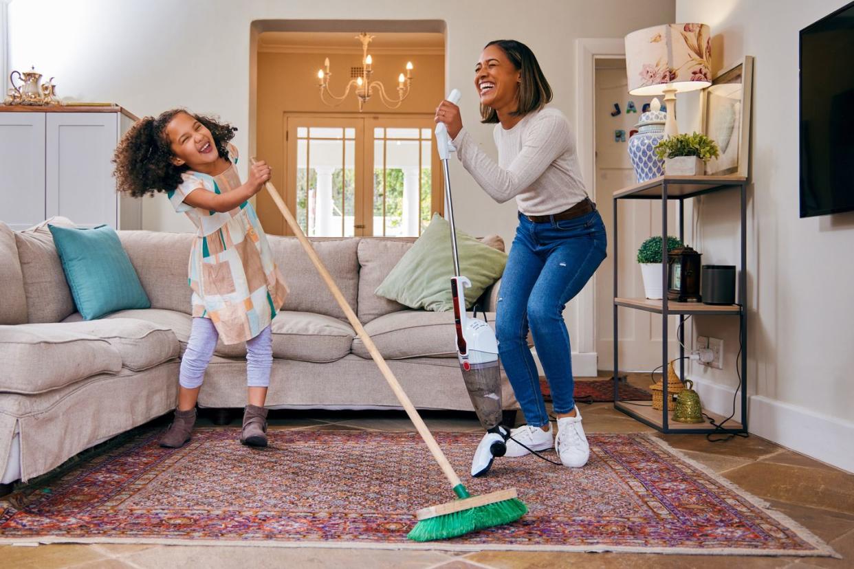 shot of a mother and daughter having fun while cleaning the living room