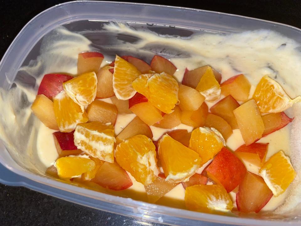 Greek yogurt with whey protein powder, orange slices, and a plum