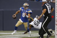 Winnipeg Blue Bombers quarterback Zach Collaros (8) gets away from Hamilton Tiger-Cats defensive end Ja'Gared Davis (56) during the first half of a Canadian Football League game Thursday, Aug. 5, 2021, in Winnipeg, Manitoba. (John Woods/The Canadian Press via AP)