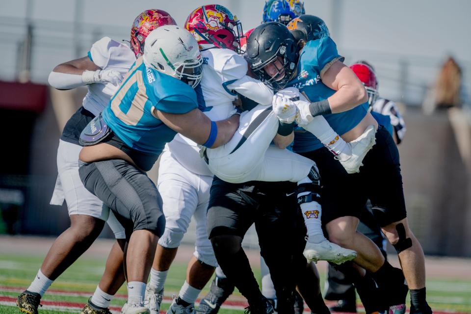 Apple Valley’s Dustin Reynolds, right, leads a group tackle for a loss during the first half of the ALADS Antelope Valley vs. Victor Valley All-Star Football Classic on Saturday, Feb. 4, 2023.