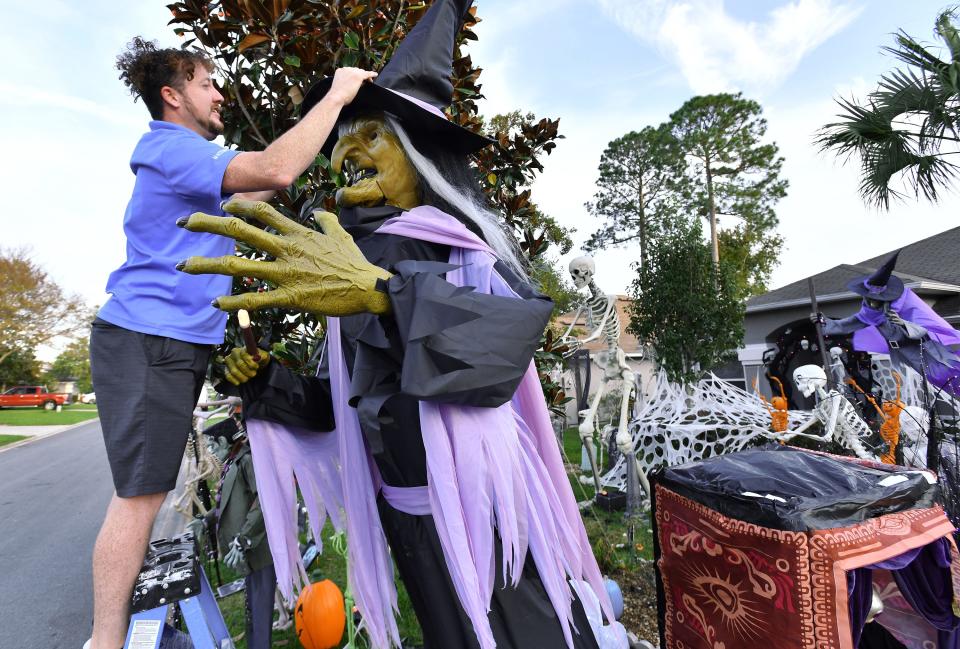 Matthew Thomas helps get Endora the witch adjusted as the wind gusts kept knocking off her hat Monday. His wife, Ashley Thomas, is raising funds for St. Jude's Children's Hospital through the elaborate Halloween display.