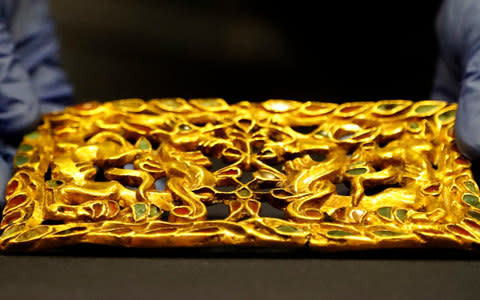 A woman adjusts a golden artefact before the opening of the Scythians: Warriors of Ancient Siberia exhibit at the British Museum - Credit: Frank Augstein/AP Photo