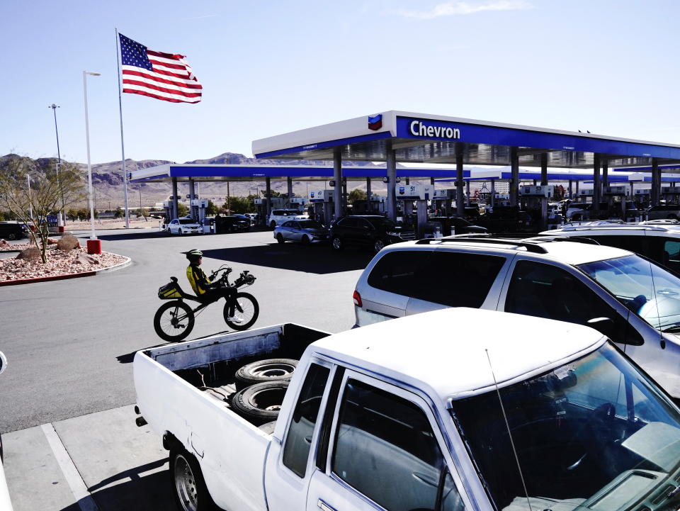 A person rides a bicycle past parked vehicles parked outside Terrible’s Road House, the world’s largest Chevron gas station, in Jean, Nevada, U.S., February 27, 2022. Picture taken February 27, 2022. REUTERS/Bing Guan