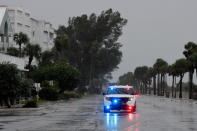 <p>Trees lean as a police car drives down a rainy road along St. Pete Beach on Sept. 28.</p>