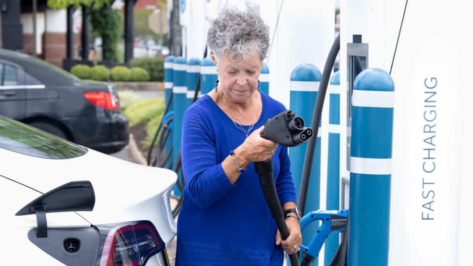 A mature woman charges her electric car.