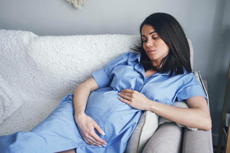 A pregnant woman sitting on the couch