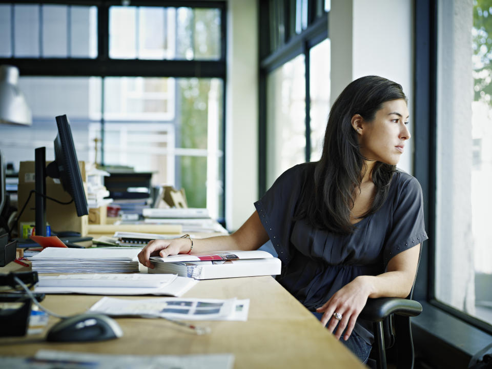 Businesswoman sitting at workstation in office looking out window