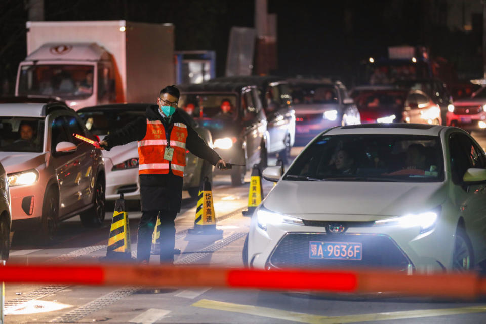 A government worker directs traffic at a toll gate in Wuhan in central China's Hubei province Tuesday, January 21, 2020.