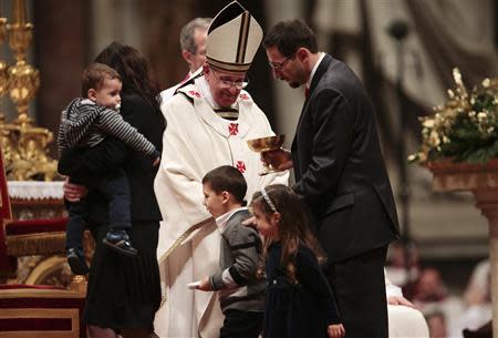 Pope Francis looks at a family during the Christmas night mass in the Saint Peter's Basilica at the Vatican December 24, 2013. REUTERS/Tony Gentile