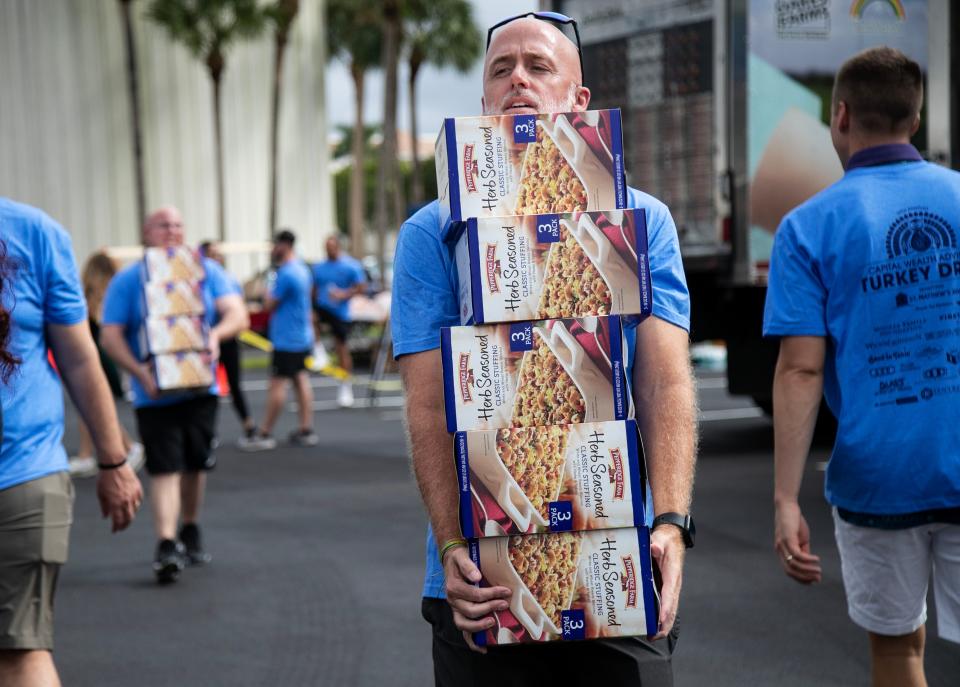 Sean Dyer carries boxes of stuffing while helping to pack boxes of food for Thanksgiving meals during the 19th Annual Capital Wealth Advisors Turkey Drop event on Monday, November 13, 2023, at First Baptist Church in Naples.